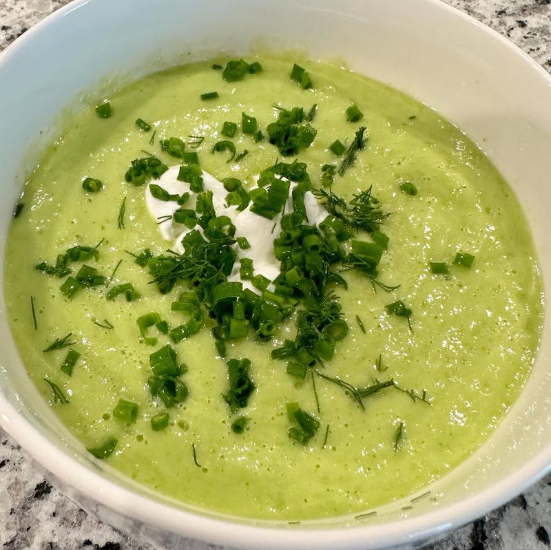 Bowl of chilled cucumber soup topped with sour cream and chives
