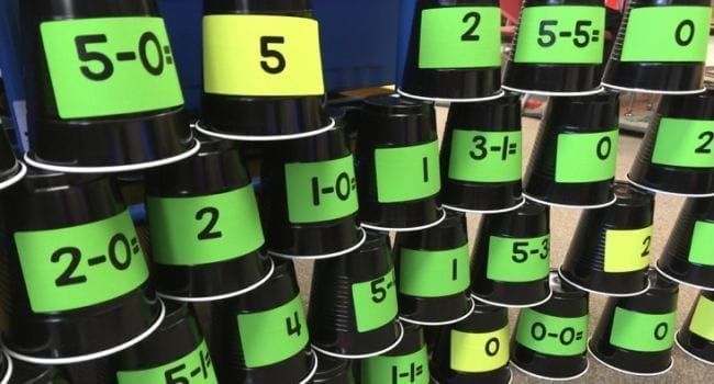 Black plastic cups with math facts and answers stacked in rows