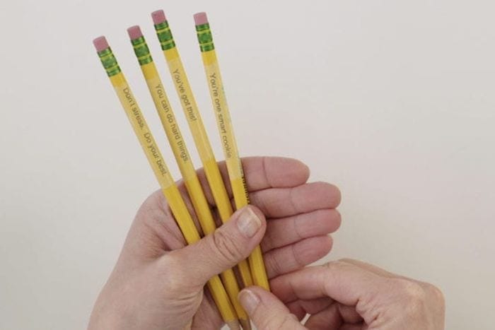 Teacher holding pencils personalized with clear tape as an example of dollar store hacks for the classroom 
