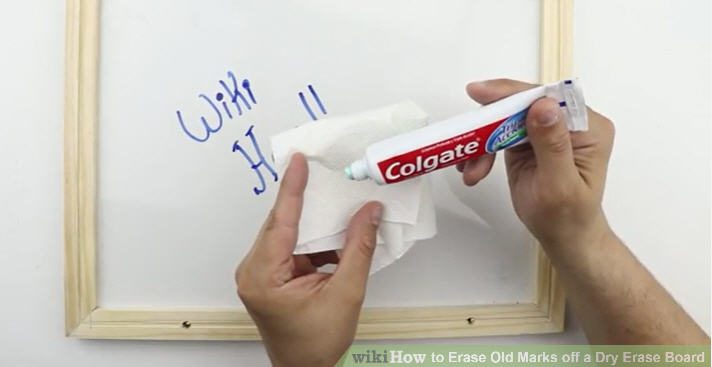 Teacher using toothpaste on a rag to clean a white board 