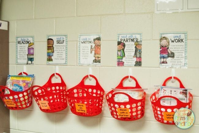 Red plastic tote baskets hung on plastic hooks on a wall as an example of dollar store hacks for the classroom 