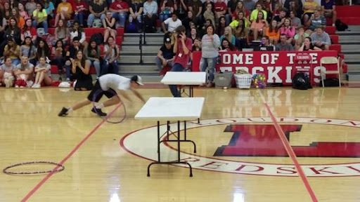 Students running under table in school gymnasium, as an example of pep rally activities and games