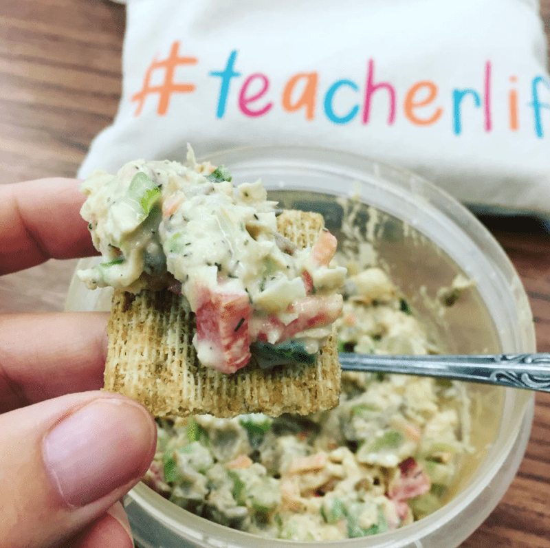 Chickpea salad on a cracker, with a pillow in the background reading #teacherlife
